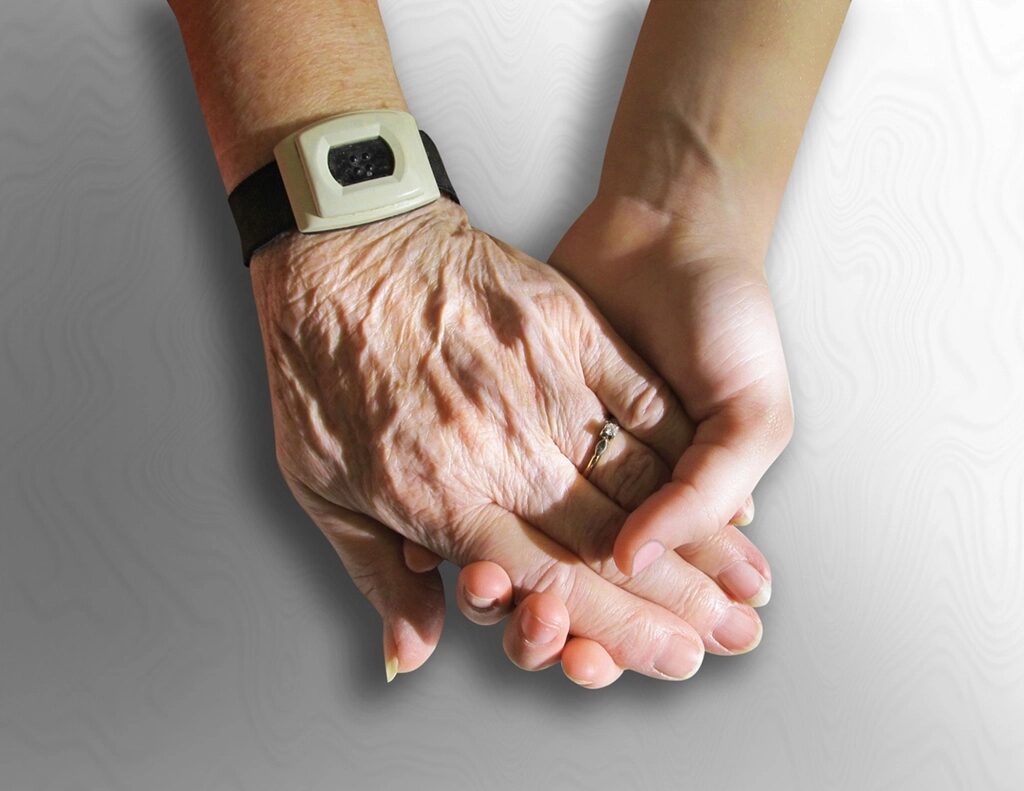 An older person's hands cupped together, held gently by a younger pair of hands.