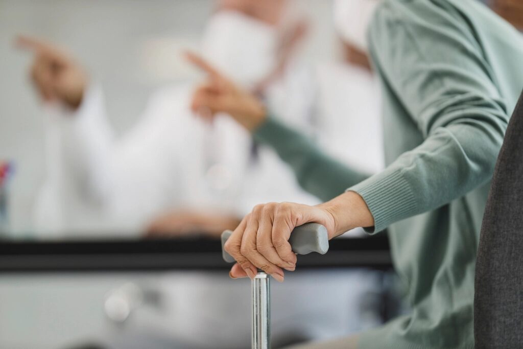 A carer walking beside an older person who is using a handrail for support.